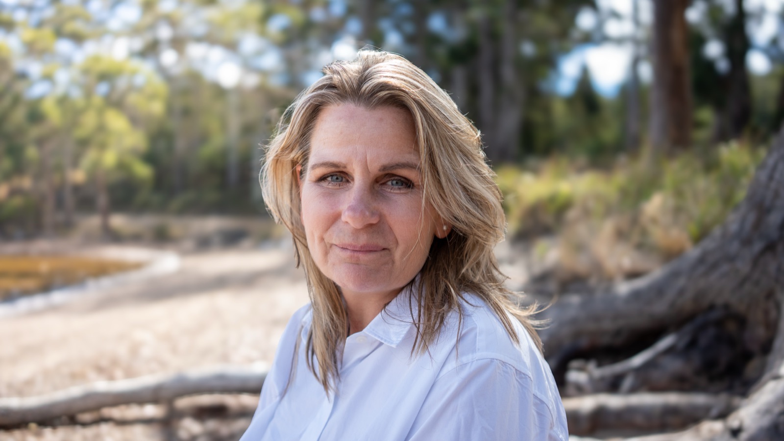 Annica Larsdotter seated on driftwood at the beach in Cygnet